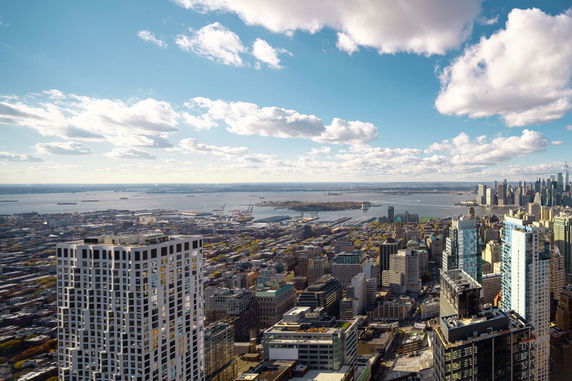 Panoramic view of a cityscape with high-rise buildings and a river in the background.