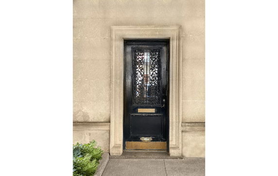 Front view of a building entrance with a decorative black door and stone surround.