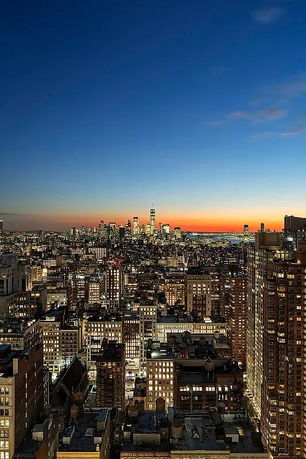 Panoramic view of a city skyline at sunset with lit buildings.