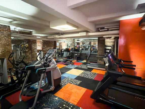 Interior of a gym area with various exercise machines and colorful flooring.