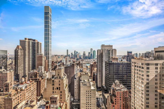 Panoramic view of a city skyline with tall buildings and a clear blue sky.