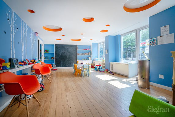 Interior view of a colorful children's play area with toys and chairs.