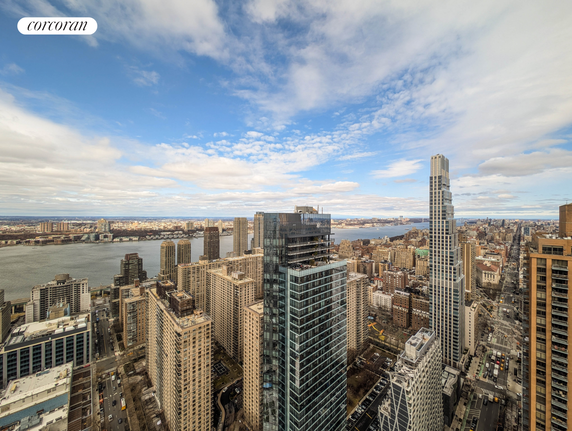 Skyline view of a city with tall buildings and a river in the background.