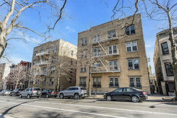 Front view of a multi-story brick apartment building with fire escapes.