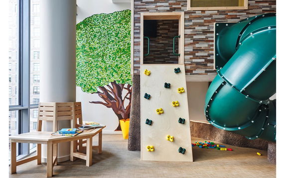 Indoor play area with a climbing wall, slide, and seating with books.