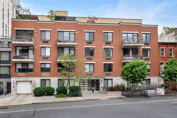Front view of a three-story brick building with balconies and a garage entrance.