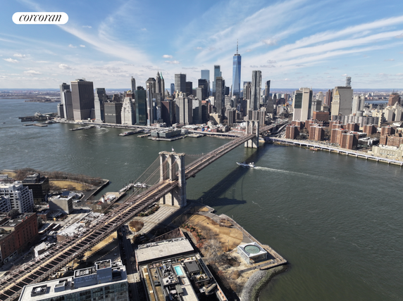 Wide view of a city skyline with a prominent bridge over water.