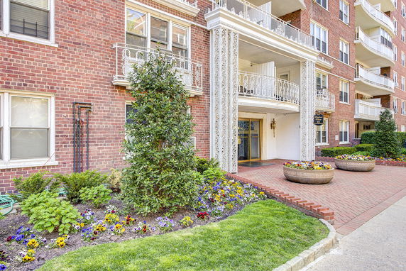Front view of a multi-story brick building with decorative balconies and flower beds.