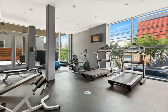 Indoor gym area with fitness equipment and large windows.