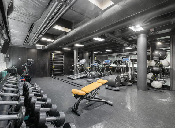 Indoor gym with exercise equipment including treadmills, dumbbells, and stationary bikes.