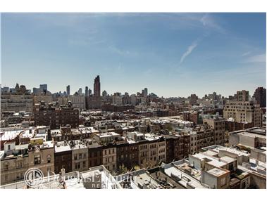 Panoramic view of a cityscape with numerous buildings under a clear blue sky.