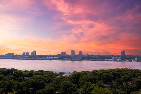 Panoramic view of a river and cityscape during sunset with colorful sky.