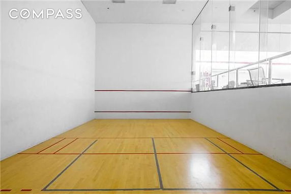 Indoor squash court with wooden flooring and white walls.