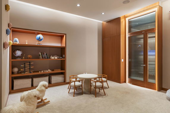 Indoor play area with a small table and chairs, shelving unit, and rocking toys.