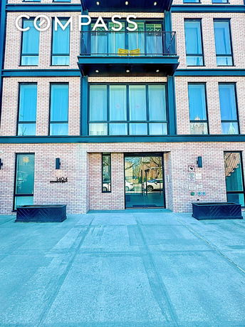 Front view of a multi-story building with large glass windows and a brick facade.