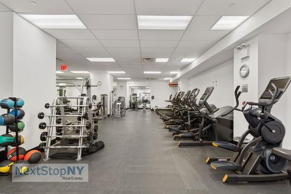 Interior of a gym with exercise machines and weights.