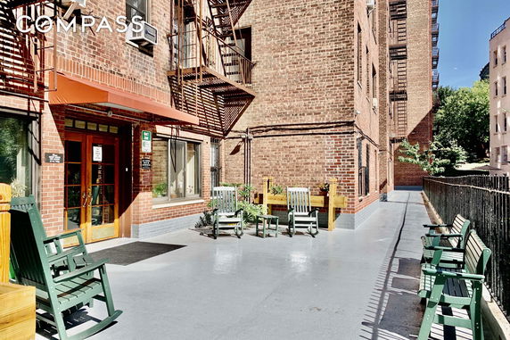 Front view of a brick building with outdoor seating area and fire escapes.