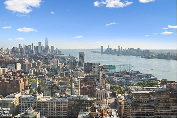 Panoramic view of a city skyline with skyscrapers and a river in the background.