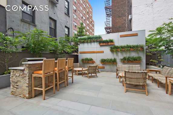 Rooftop seating area with chairs, table, and vertical garden in a residential building.