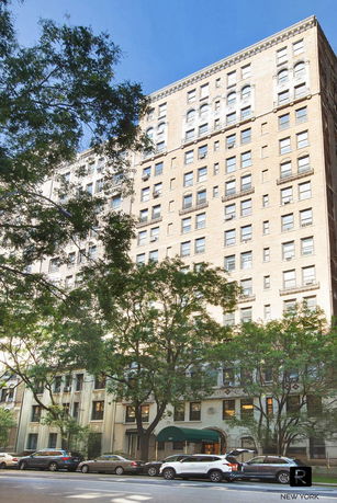 Front view of a multi-story apartment building with arched windows and a beige facade.