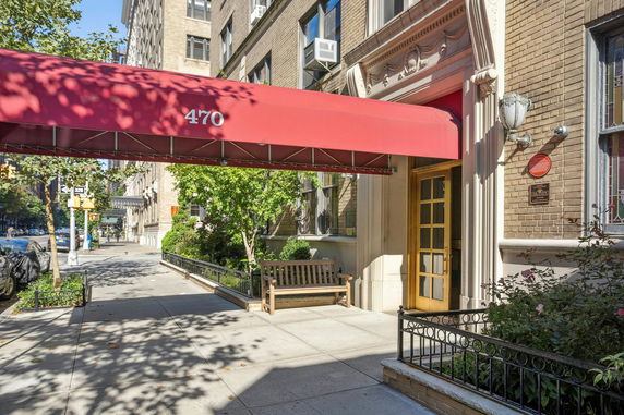 Front view of a building entrance with a red awning and bench.