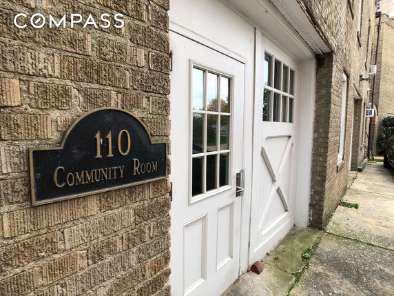 Exterior view of a building with a sign marked 'Community Room 110' next to a white door.