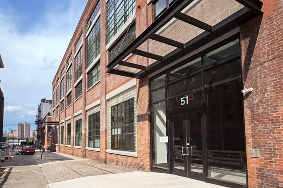 Front view of a multi-story brick building with large glass windows and a metal canopy.