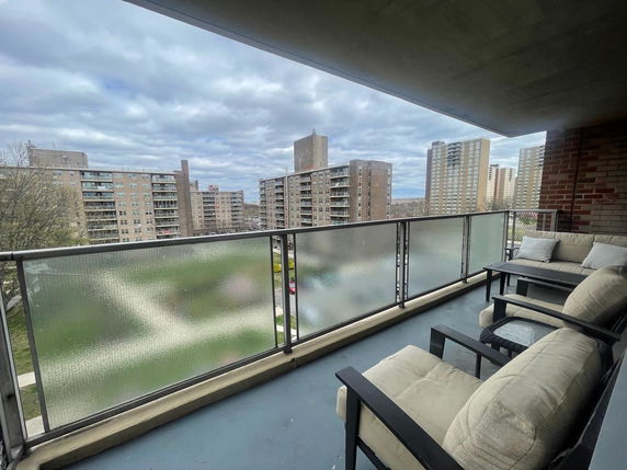 View of surrounding buildings from a balcony with seating.