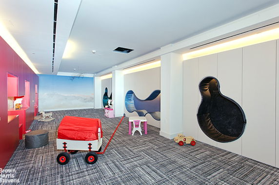 Indoor children's play area with toys and play structures.