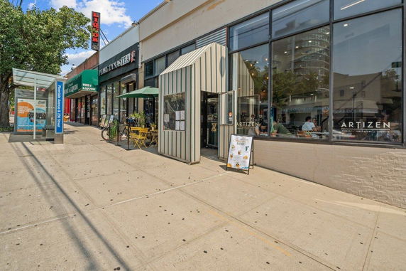 Front view of a commercial building with large windows and outdoor seating.