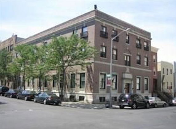 Front view of a multi-story brick building on a street corner.