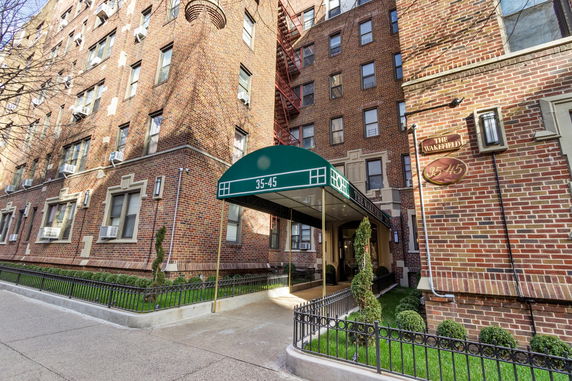 Front view of a multi-story brick building with a green awning and entrance.