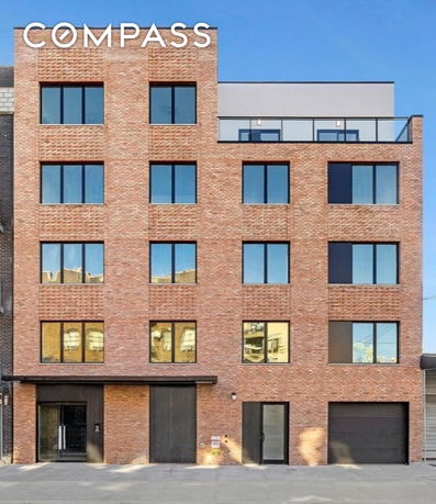 Front view of a brick residential building with multiple windows and a rooftop terrace.