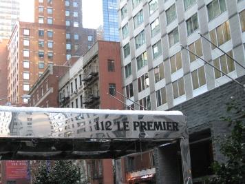 Front view of multiple multi-story buildings along a street with an entrance awning in the foreground.