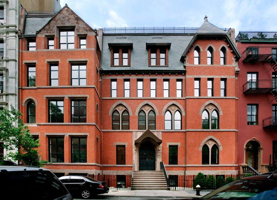 Front view of a multi-story brick building with arched windows and a central entrance.