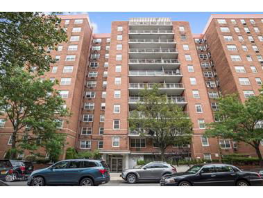 Front view of a multi-story brick apartment building with balconies.
