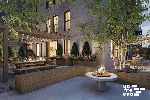 Outdoor patio area with seating and string lights, adjacent to a building.