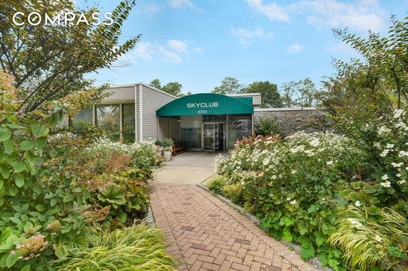 Front view of a building with a canopy entrance and garden.