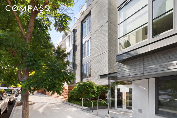 Front view of a modern multi-story building with large windows and a sidewalk entrance.