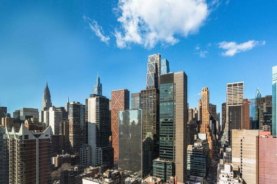 Panoramic view of a city skyline with tall skyscrapers under a blue sky.