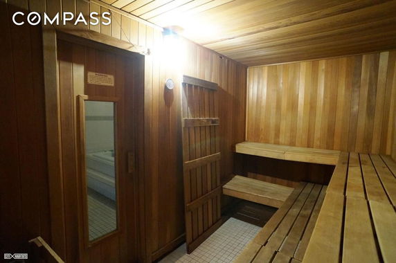 Interior of a wooden sauna room with benches and a glass door.