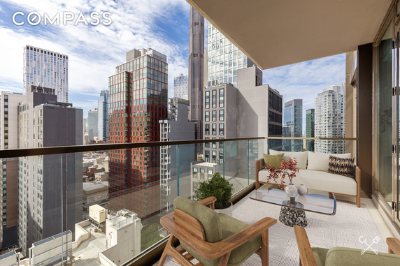Panoramic view from a high-rise balcony showing cityscape and tall buildings.
