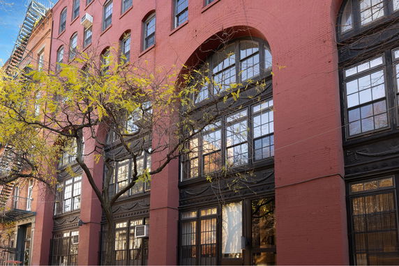 Front view of a brick multi-story building with large arched windows.