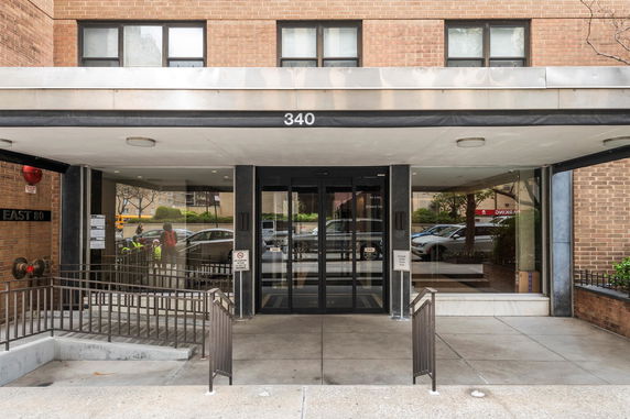 Front view of a multi-story building entrance with glass doors and a ramp.