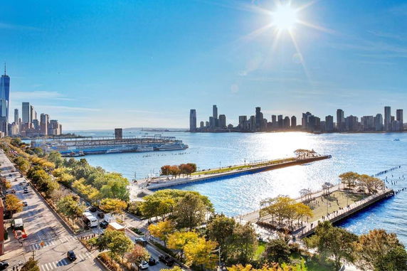 Wide angle view of a waterfront city skyline with parks, a river, and skyscrapers.