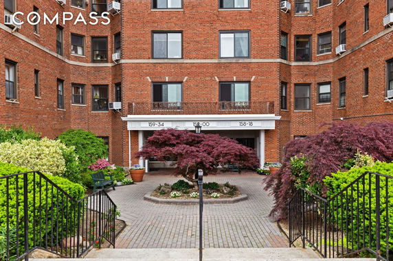 Front view of a multi-story brick building with landscaped entrance.