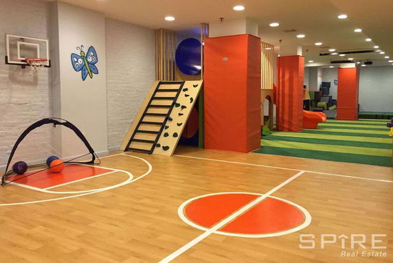 Indoor play area with a basketball hoop, climbing wall, and soft play equipment.