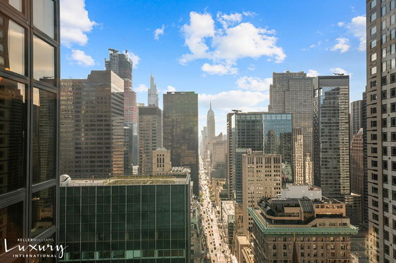 Panoramic view of a city skyline with tall buildings and a clear blue sky.