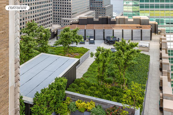 Rooftop garden with seating area and greenery on a building.