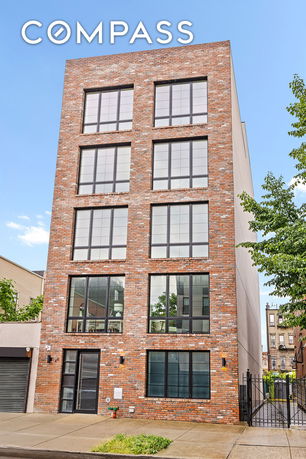 Front view of a multi-story brick building with large windows.